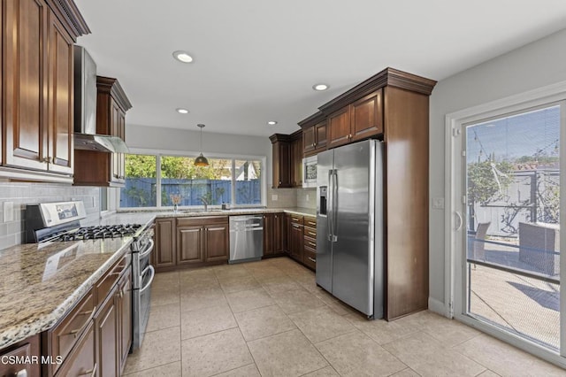 kitchen with sink, stainless steel appliances, wall chimney exhaust hood, and tasteful backsplash