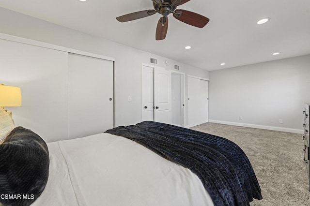 carpeted bedroom featuring ceiling fan and multiple closets