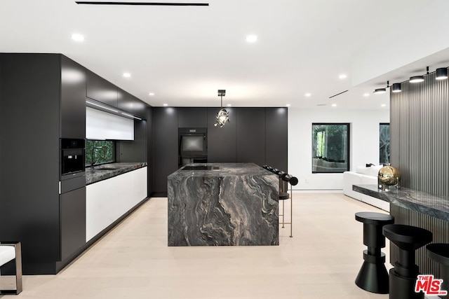 kitchen featuring pendant lighting, light wood-type flooring, a barn door, and a center island