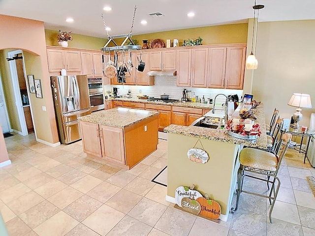 kitchen with hanging light fixtures, a kitchen breakfast bar, kitchen peninsula, stainless steel appliances, and backsplash