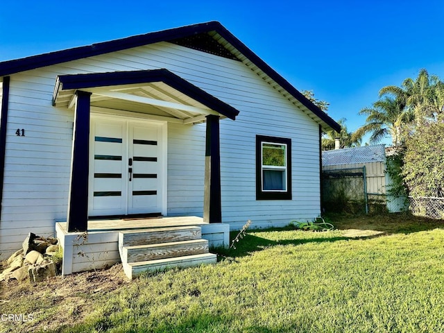 back of property with a lawn and french doors