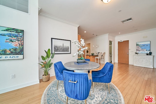 dining space featuring ornamental molding and light hardwood / wood-style floors