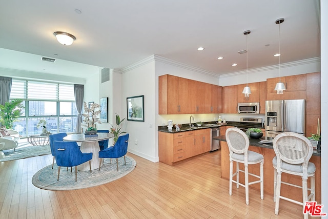 kitchen featuring stainless steel appliances, sink, light hardwood / wood-style floors, and decorative light fixtures