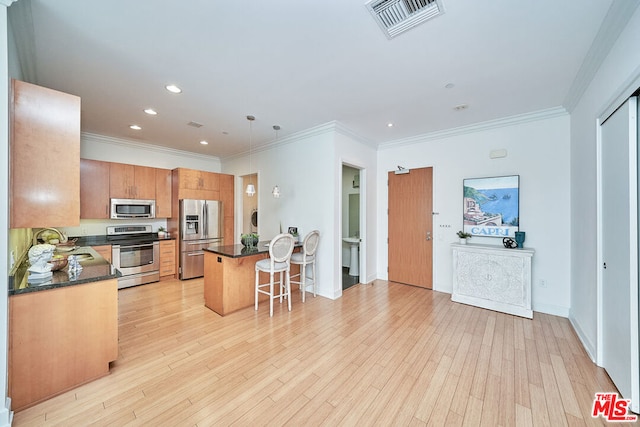 kitchen featuring decorative light fixtures, light hardwood / wood-style floors, a kitchen bar, sink, and stainless steel appliances