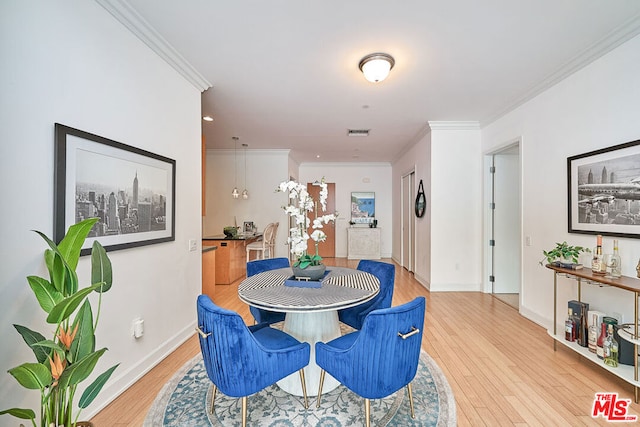 dining space with light wood-type flooring and crown molding