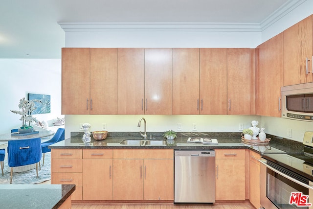 kitchen with sink, appliances with stainless steel finishes, crown molding, and dark stone counters