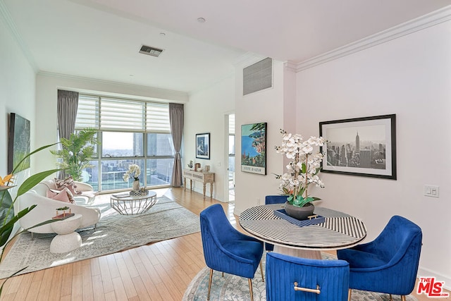 dining space featuring light hardwood / wood-style flooring and crown molding