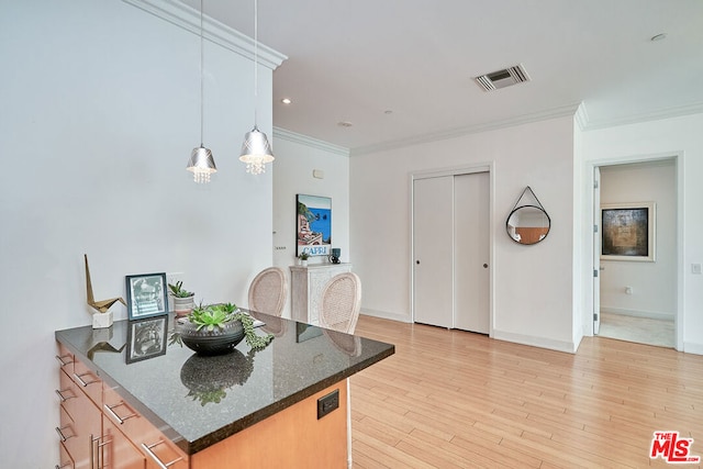 kitchen with light hardwood / wood-style floors, hanging light fixtures, crown molding, and dark stone countertops