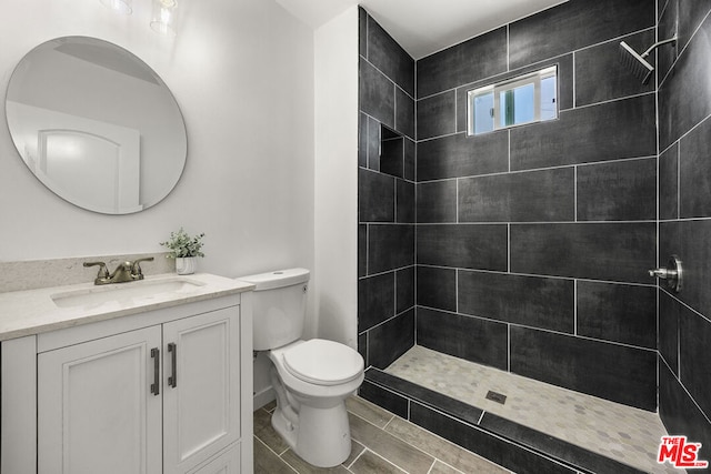 bathroom featuring tiled shower, vanity, and toilet