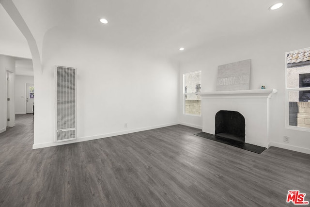 unfurnished living room featuring plenty of natural light and dark hardwood / wood-style flooring