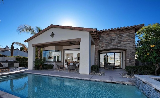 rear view of house featuring exterior kitchen, a patio area, an outbuilding, and pool water feature