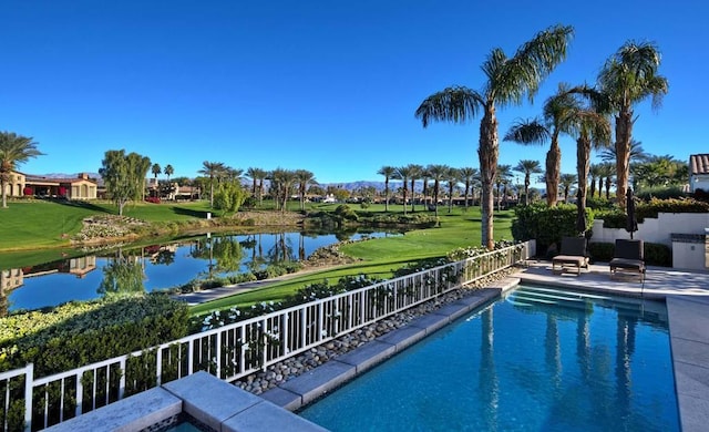 view of swimming pool featuring a lawn, a water view, and a patio