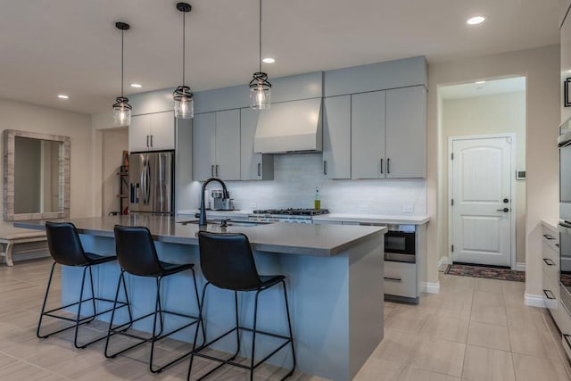 kitchen with appliances with stainless steel finishes, sink, backsplash, and an island with sink