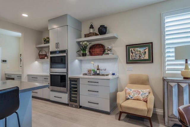 kitchen with stainless steel double oven and beverage cooler