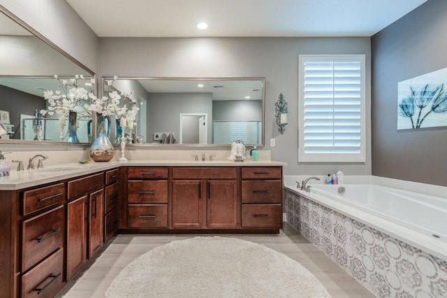 bathroom with vanity, a wealth of natural light, and a relaxing tiled tub