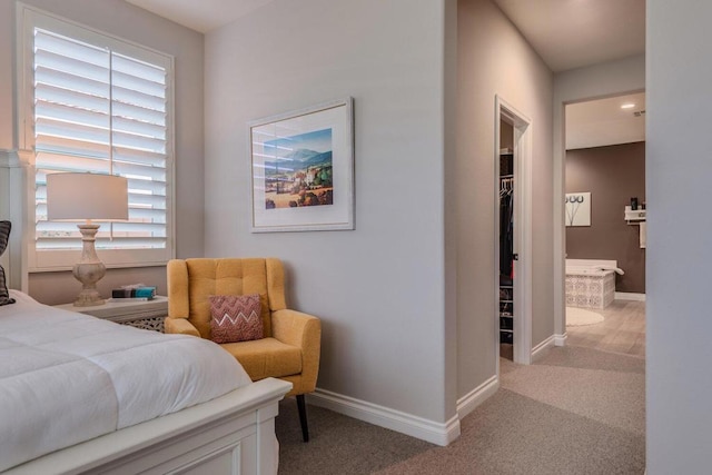 bedroom with ensuite bathroom, light carpet, and multiple windows