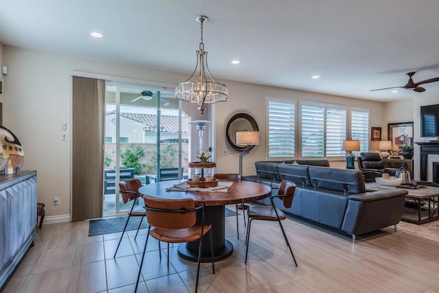 dining space with light tile patterned floors and ceiling fan with notable chandelier