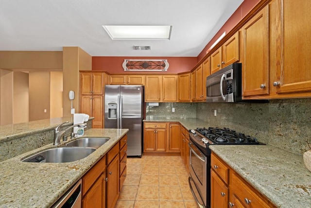 kitchen featuring light tile patterned floors, appliances with stainless steel finishes, tasteful backsplash, light stone countertops, and sink