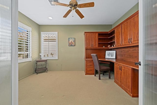 carpeted office space with ceiling fan and built in desk