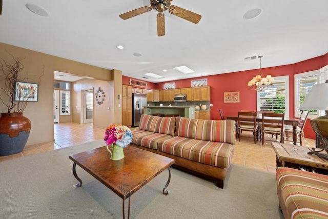 tiled living room with ceiling fan with notable chandelier