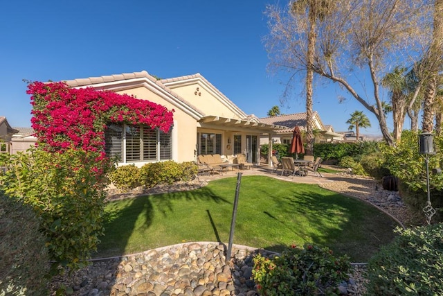 back of property with a yard and a patio