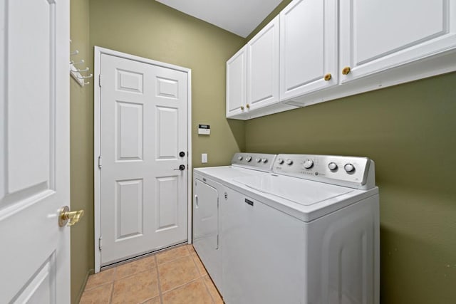 clothes washing area with washer and dryer, cabinets, and light tile patterned floors