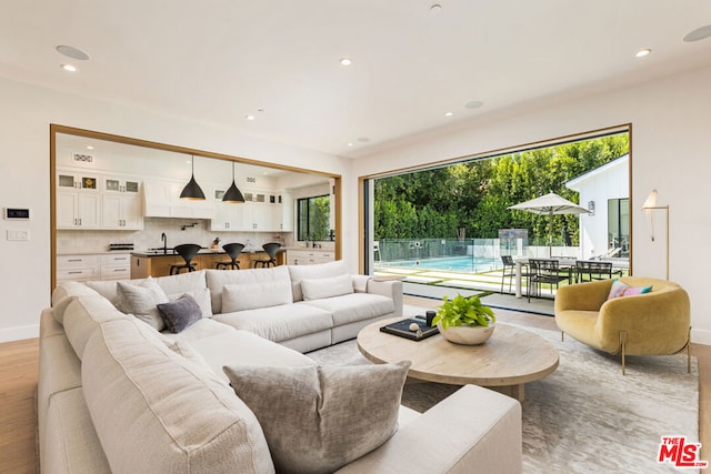 living room with plenty of natural light, sink, and light hardwood / wood-style flooring