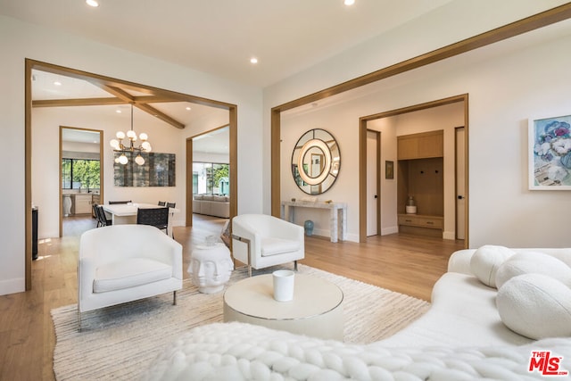 living room featuring an inviting chandelier, light hardwood / wood-style flooring, and lofted ceiling with beams