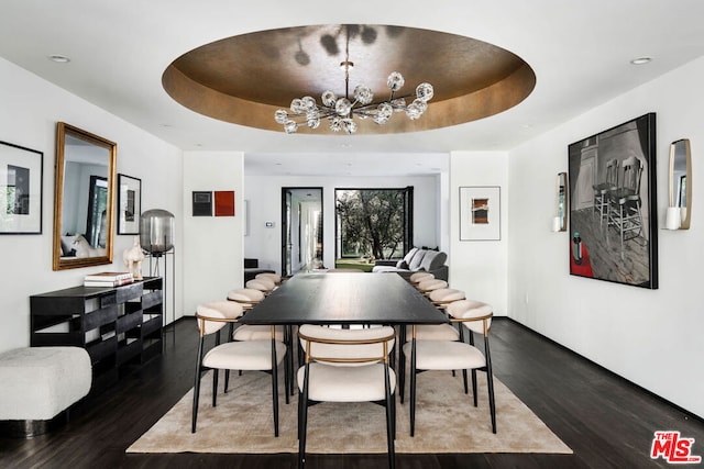 dining area featuring a tray ceiling, dark hardwood / wood-style flooring, and a chandelier