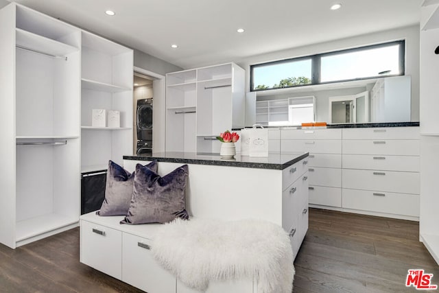 spacious closet featuring stacked washer and dryer and dark wood-type flooring