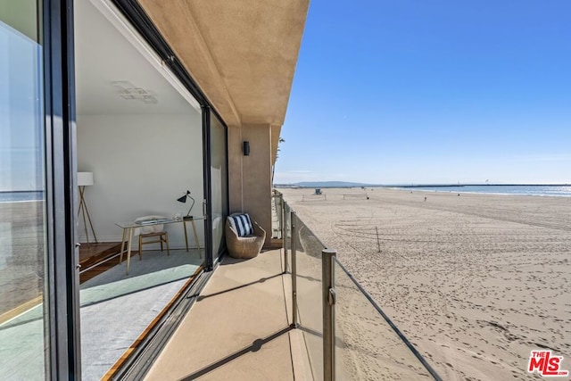 balcony featuring a water view and a beach view