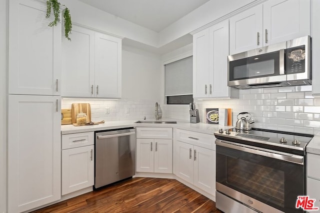 kitchen featuring appliances with stainless steel finishes, white cabinetry, dark hardwood / wood-style flooring, sink, and backsplash