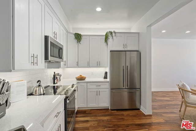 kitchen featuring light stone counters, appliances with stainless steel finishes, dark hardwood / wood-style flooring, and tasteful backsplash