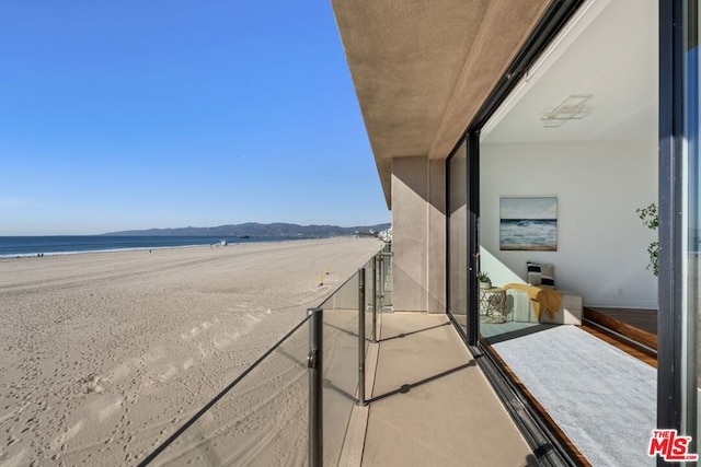 balcony with a water view and a view of the beach