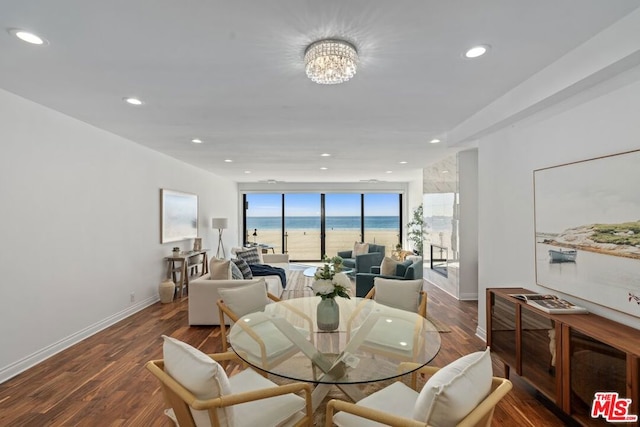 dining room with dark hardwood / wood-style floors, a notable chandelier, and a water view