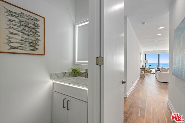 hall with a water view, wood-type flooring, and sink