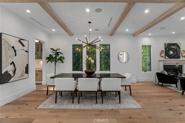 dining room featuring beam ceiling, an inviting chandelier, and light hardwood / wood-style flooring