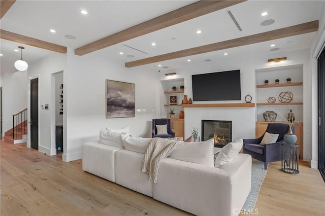 living room featuring light wood-type flooring and built in shelves