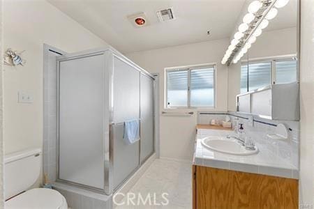 bathroom featuring a shower with shower door, vanity, and toilet