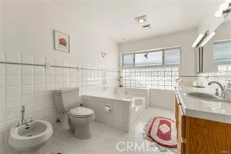 bathroom with a bidet, a tub, tile walls, and vanity