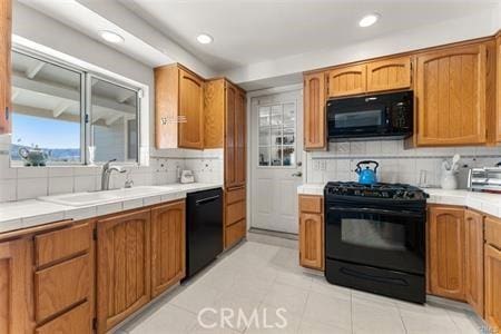 kitchen featuring black appliances, tile counters, decorative backsplash, sink, and light tile patterned floors