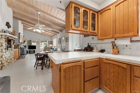 kitchen with ceiling fan, tile countertops, lofted ceiling with beams, kitchen peninsula, and wood ceiling