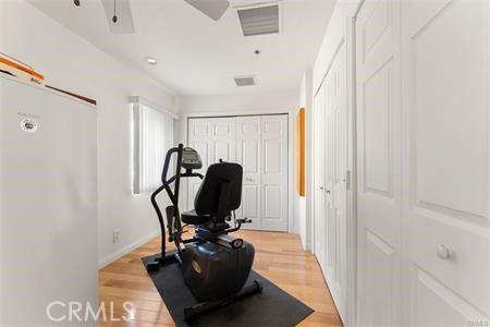 workout area with ceiling fan and light hardwood / wood-style flooring