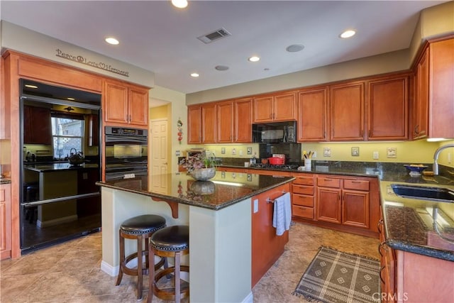 kitchen with a kitchen island, sink, dark stone countertops, and black appliances