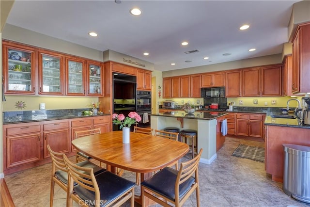 kitchen with recessed lighting, visible vents, a kitchen island, a sink, and black appliances