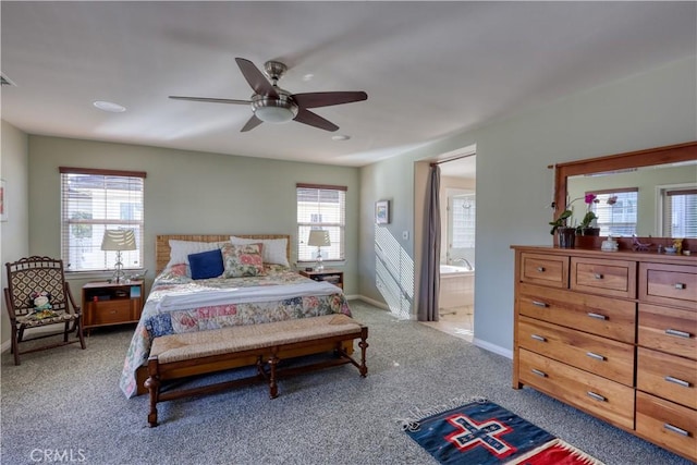 bedroom featuring light carpet, ceiling fan, ensuite bath, and baseboards