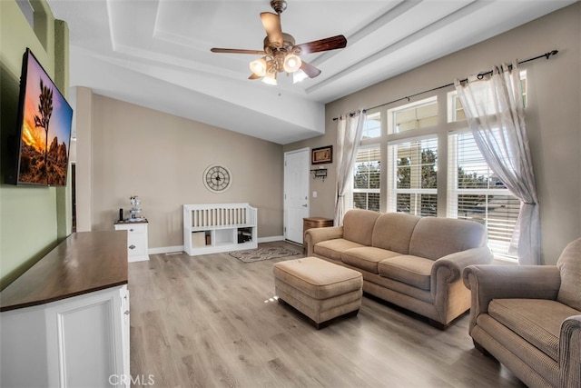 living room featuring ceiling fan, light hardwood / wood-style floors, and a tray ceiling