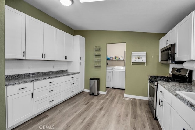 kitchen featuring washing machine and clothes dryer, stainless steel appliances, and white cabinetry