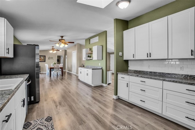 kitchen with ceiling fan, white cabinets, backsplash, and light hardwood / wood-style floors