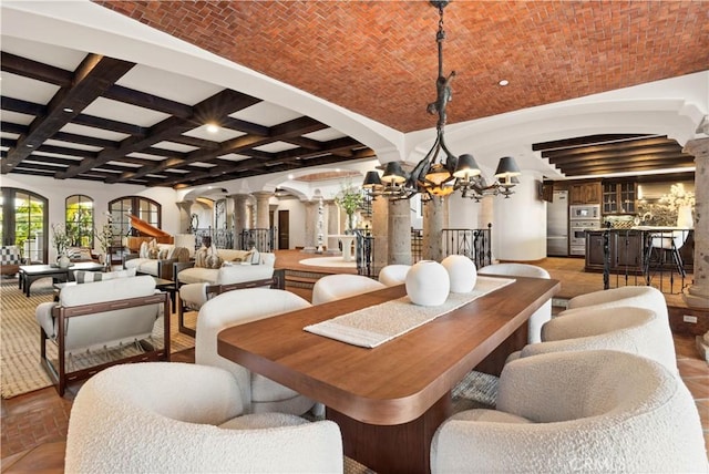 dining area featuring beam ceiling, brick ceiling, a chandelier, and ornate columns